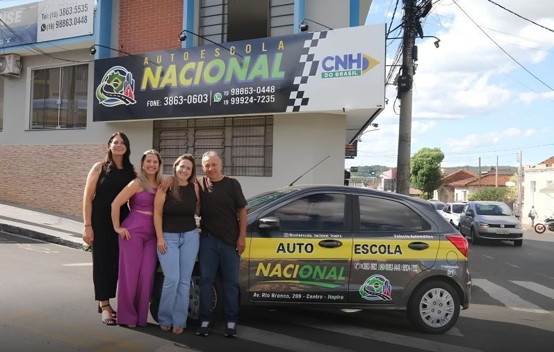 Equipe da Auto Escola Nacional em frente à fachada com veículo oficial